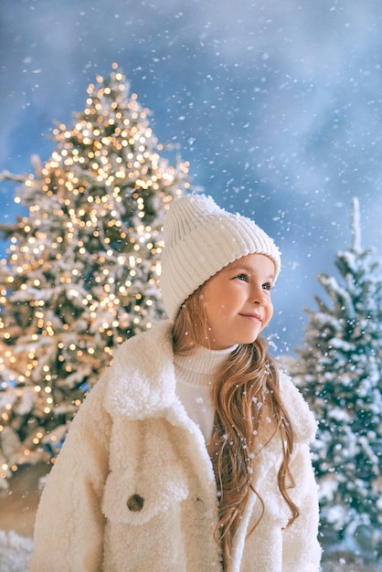Caucasian blonde girl in white eco fur coat hat et gants marchant dans la forêt de noël d'hiver