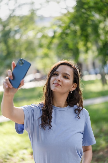 Caucasian girl adolescente étudiante utilisant un smartphone prenant un selfie à l'extérieur dans le parc de la ville