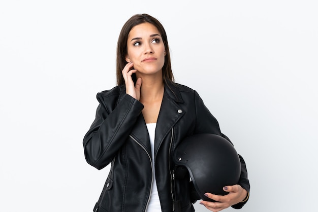 Caucasian girl tenant un casque de moto sur blanc pensant une idée