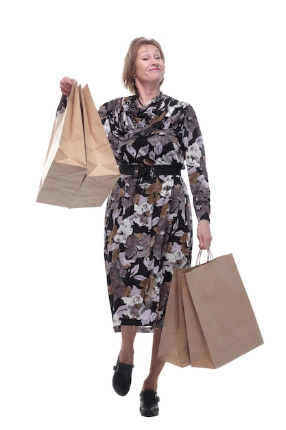 Caucasian senior woman walking with shopping bags smiling at viewer