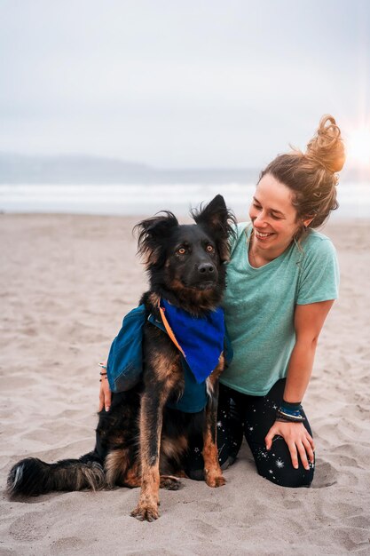 Caucasian woman smiling sur la plage avec son chien