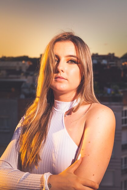 Caucasian young girl posing pendant le coucher du soleil dans un toit avec une belle vue sur Donostia-San Sebastian, Pays Basque.