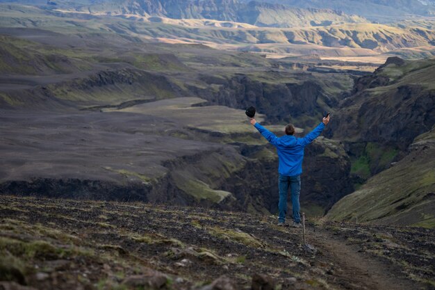 Caucasian young guy standing in over mountain and canyon background sur le chemin du sentier Laugavegur, Islande. Promouvoir un mode de vie sain.