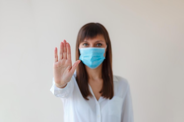 Photo caucasian young woman showing palm hand stop no sign wearing protective respiratory mask for prevent infection medical concept from outbreak covid 19 virus cold respiratory disease