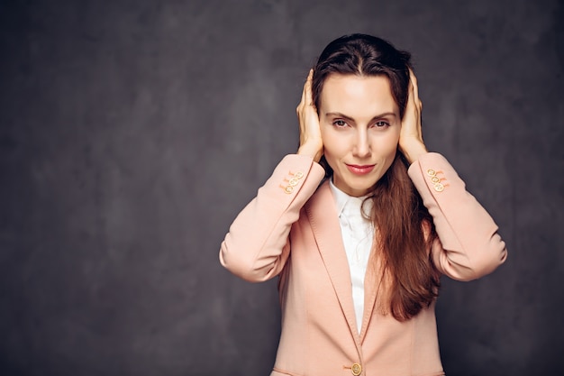 Caucasien adulte femme couvrant les oreilles sur fond gris foncé