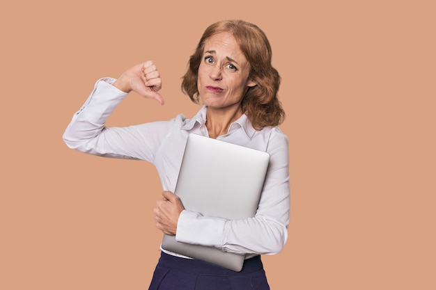 Photo caucasien d'âge moyen avec un ordinateur portable en studio montrant un geste d'indifférence pouce vers le bas concept de désaccord