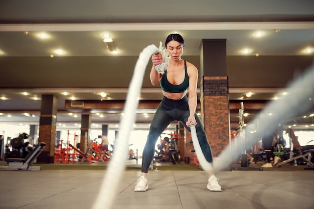 Caucasien, ajustement, femme, habillé, dans, sportsoutfit, séance entraînement, à, bataille, cordes, à, gymnase