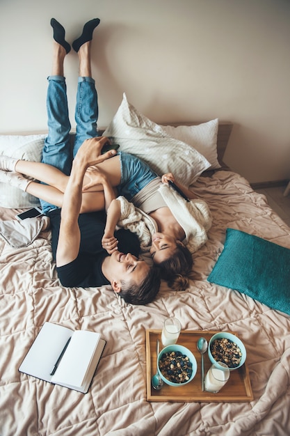 Caucasien couple est assis dans son lit à l'envers faisant un selfie avant de manger des céréales avec du lait