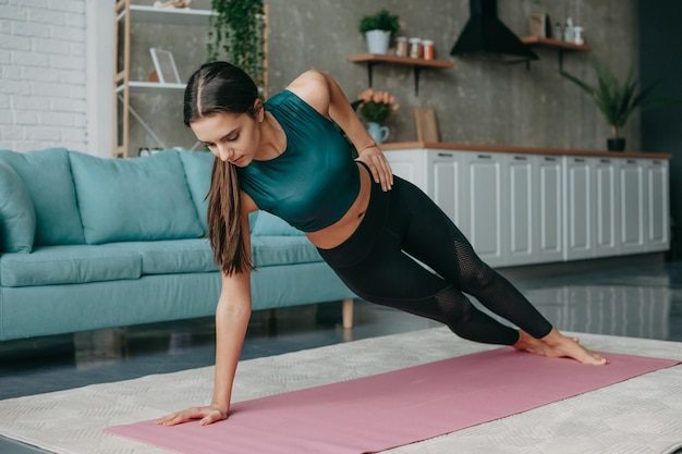 Caucasien debout en planche latérale d'une part à la maison entraînement des muscles du corps santé mode de vie fitness