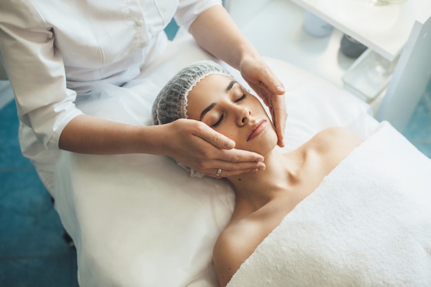 Caucasien femme allongée sur un canapé au salon spa ayant un massage du visage