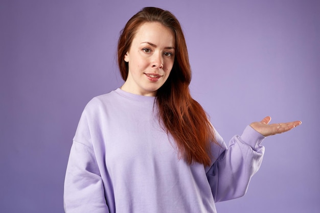 Caucasien, femme, dans, violet, sweat-shirt, regard naturel, sourire, long, cheveux rouges, arrière-plan violet