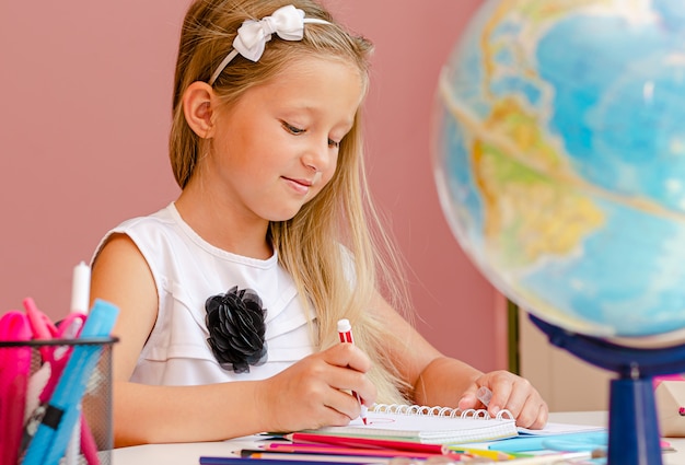 Caucasien fille souriante est dong ses devoirs pour la leçon préscolaire