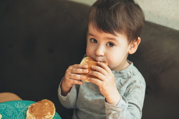 Caucasien garçon regardant la caméra o tout en mangeant de délicieux gâteaux à la maison