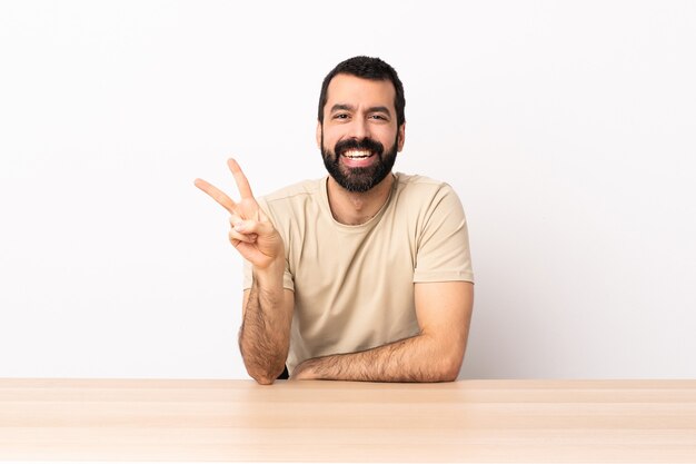 Caucasien, homme, à, barbe, dans, a, table, sourire, et, projection, signe victoire