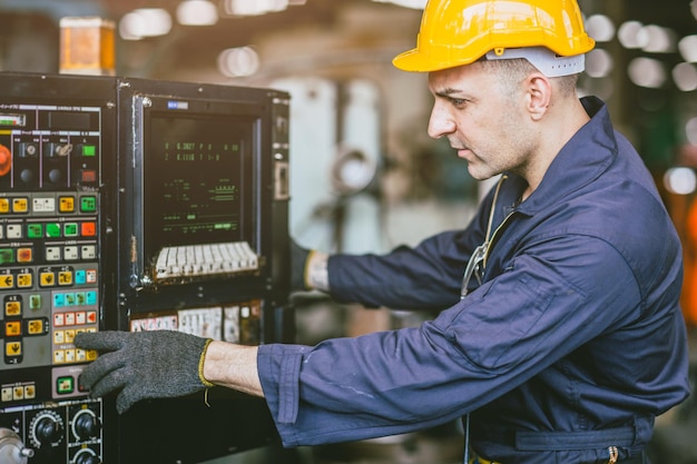 Caucasien ingénieur travailleur de compétence masculine travaillant faire fonctionner la machine de tour CNC dans l'usine de métal