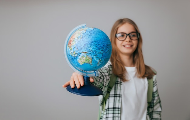 Photo caucasien jeune adolescent écolière étudiant tenant un globe sur un fond gris isolé happy earth day