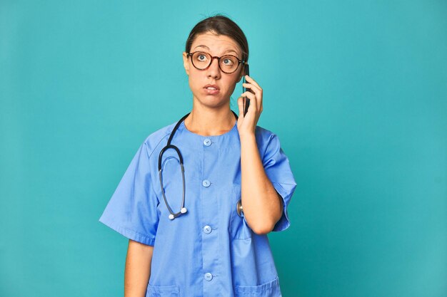 Caucasien jeune infirmière parlant au téléphone studio photo