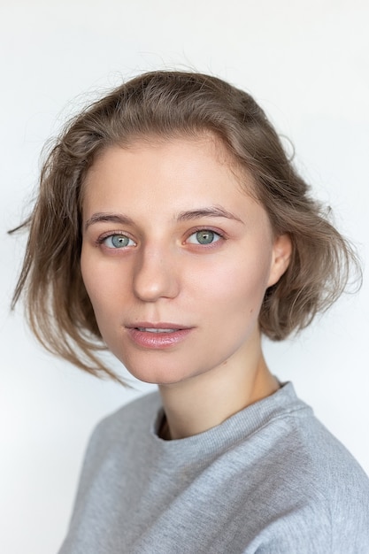 Caucasienne femme avec une peau propre et des cheveux courts posant en t-shirt gris