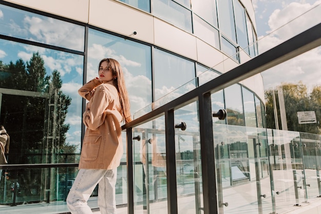 Caucasienne jeune femme assez élégante debout près de la balustrade de balcon en verre du centre de bureau d'affaires