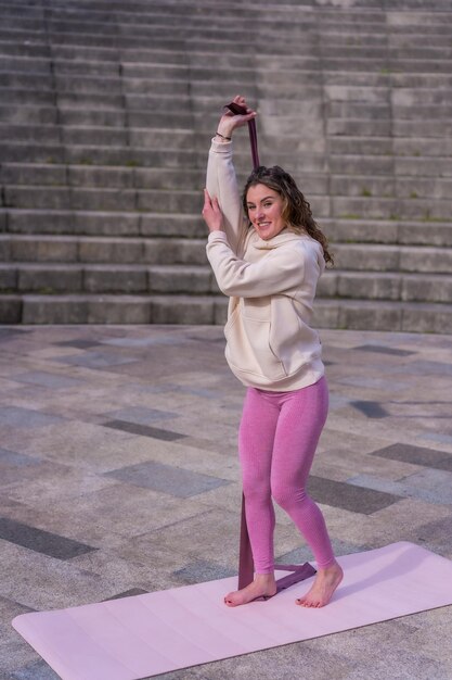 Caucasienne jeune femme faisant du fitness dans un parc de la ville exerce avec le caoutchouc