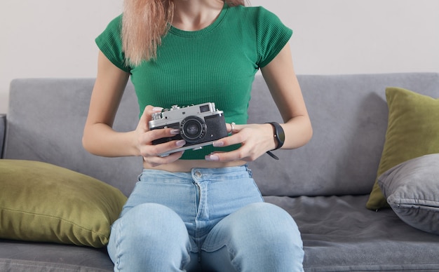 Caucasienne jeune fille tenant un vieil appareil photo à la maison.