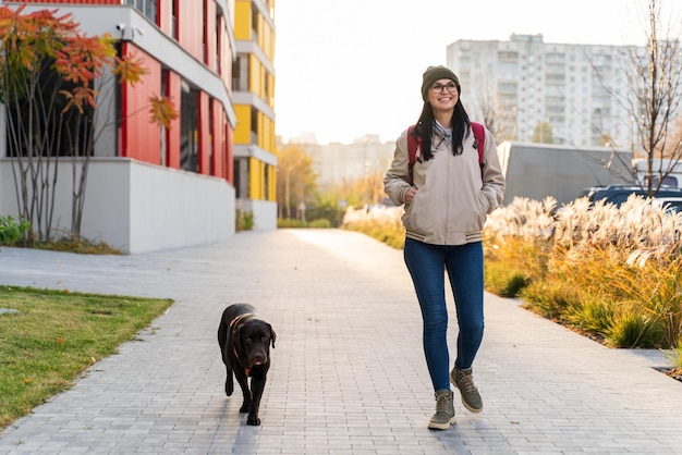 Caucasienne magnifique femme regardant loin tout en marchant avec son chien dans la rue et profitant d'un bon temps ensoleillé Marcher et prendre soin du concept d'animal de compagnie
