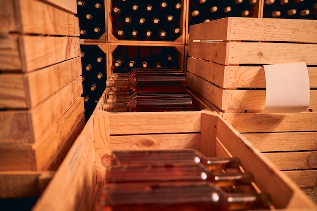 Cave à vin ou local de stockage avec bouteilles de boisson alcoolisée dans des caisses en bois et des casiers à vin