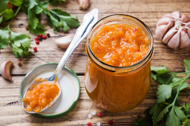 Caviar fait maison à partir de courgettes, tomates et oignons, dans un bocal en verre recouvert de bois. Mise en conserve de la production maison, légume en conserve.