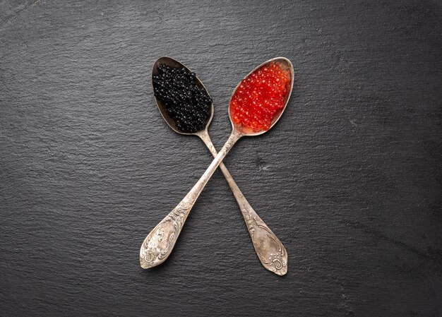 Photo caviar granuleux de poisson-pêche et caviar de saumon rouge dans une cuillère à fond noir vue de haut