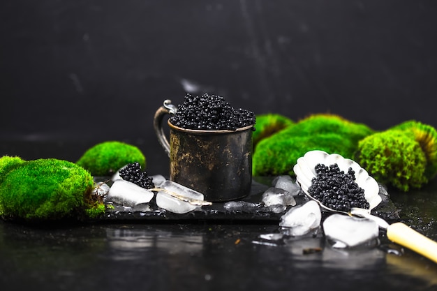 Caviar noir dans un bol. Gros plan de caviar noir d'esturgeon naturel de haute qualité. Épicerie fine. Texture du plat carré de caviar de luxe cher sur fond noir