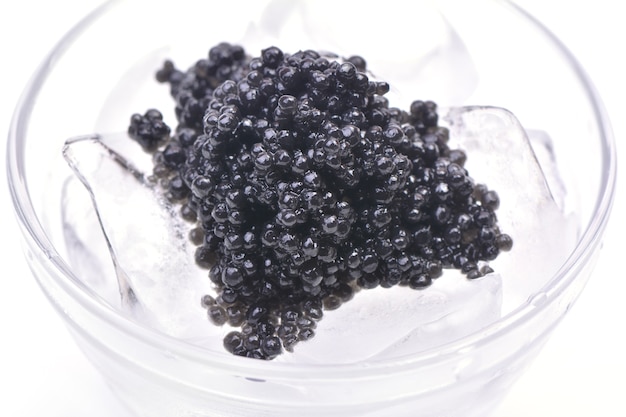 Caviar noir dans la glace isolé sur blanc