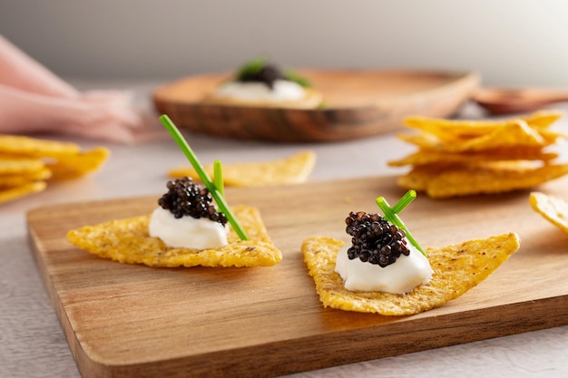 Photo caviar noir sur des nachos avec de la crème aigre sur une planche à couper en bois