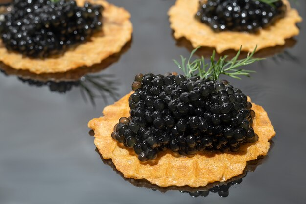 Caviar noir en tartelettes sur fond sombre. Concept d'alimentation saine. Espace de copie.