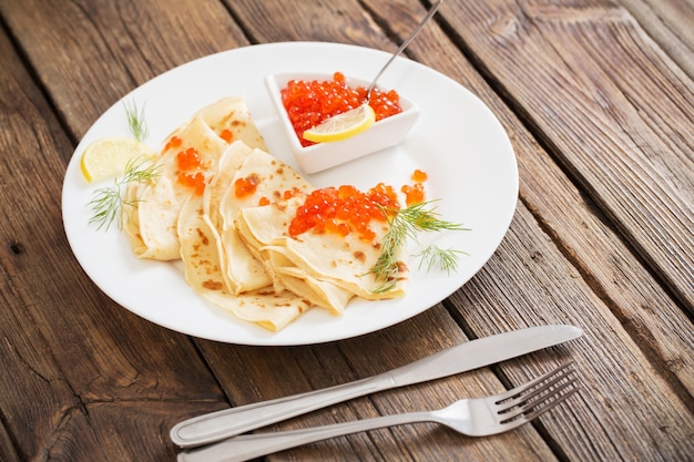 Caviar rouge avec crêpes sur table en bois