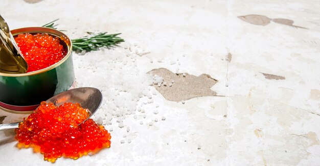 Caviar rouge dans un bocal avec une cuillère sur fond rustique