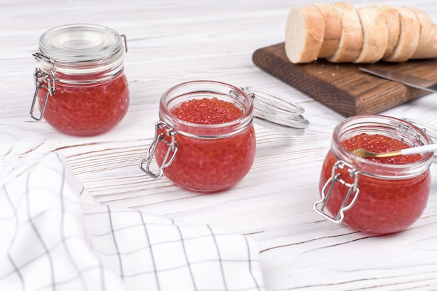 Caviar rouge dans un bocal en verre sur bois blanc vieilli