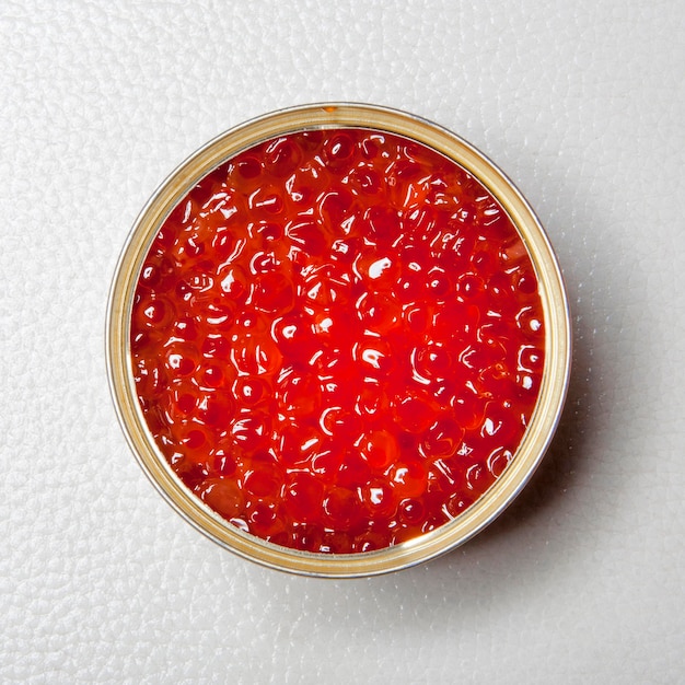 Caviar rouge dans la boîte de conserve ouverte sur fond blanc