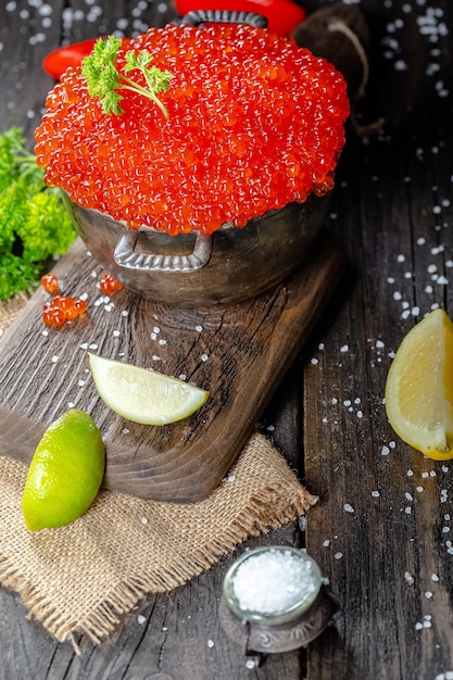 caviar rouge dans un style vintage rustique, un bol profond de casserole de seaux, sur une planche à découper en bois et t