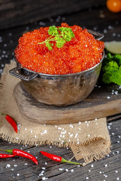 caviar rouge dans un style vintage rustique, un bol profond de casserole de seaux, sur une planche à découper en bois et