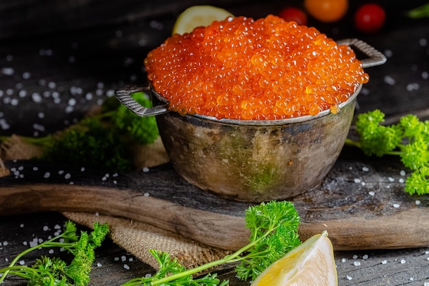 caviar rouge dans un style vintage rustique, un bol profond de casserole de seaux, sur une planche à découper en bois