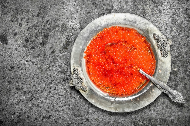 Caviar rouge dans une vieille soucoupe. Sur fond rustique.