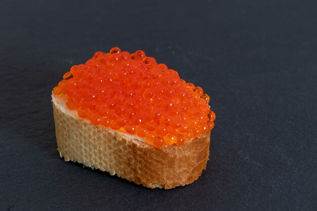 Caviar rouge avec du pain blanc sur la planche de pierre grise