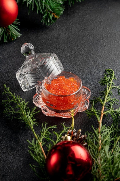 Caviar rouge sur fond sombre de Noël décoré de jouets et de branches