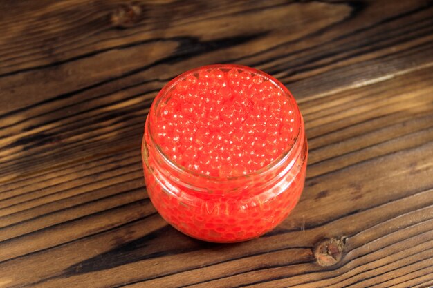 Caviar rouge en pot de verre sur table en bois