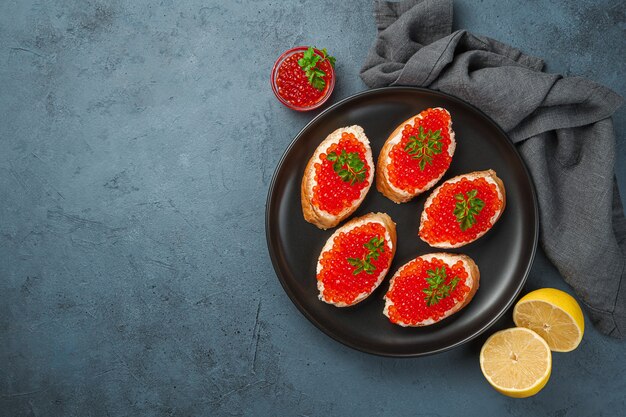 Caviar rouge sur toast au beurre sur fond sombre au citron