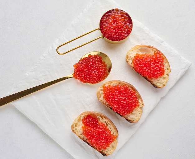 Caviar rouge sur des tranches de pain de blé blanc sur une table blanche concept de cuisine de luxe et gourmet