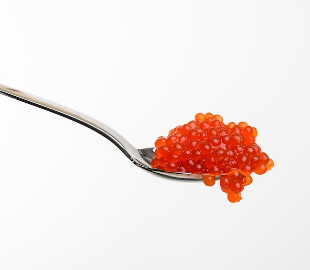 Caviar de saumon kéta rouge à grains frais dans une cuillère métallique, fond blanc, Close up