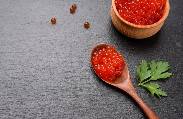 Caviar de saumon kéta rouge granuleux frais dans une cuillère en bois, nourriture délicieuse et saine, gros plan