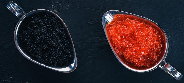 Caviar de saumon rouge et caviar d'esturgeon noir Sur un fond en bois Vue de dessus Espace libre pour le texte