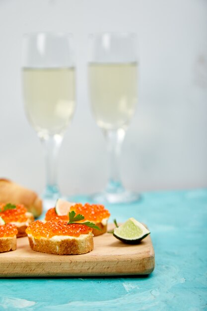 Caviar de saumon rouge dans un bol et des sandwichs avec sur une planche à découper en bois